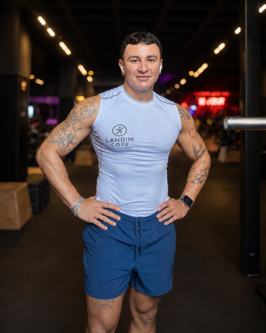 Carlos Eduardo Landim de pé numa academia, mãos na cintura, vestindo camiseta do Landim Core